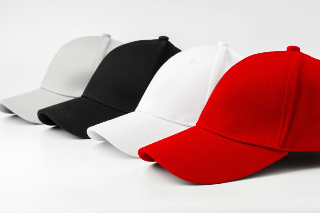 Lineup of Four Blank Baseball Caps in Red, White, and Black on a White Background